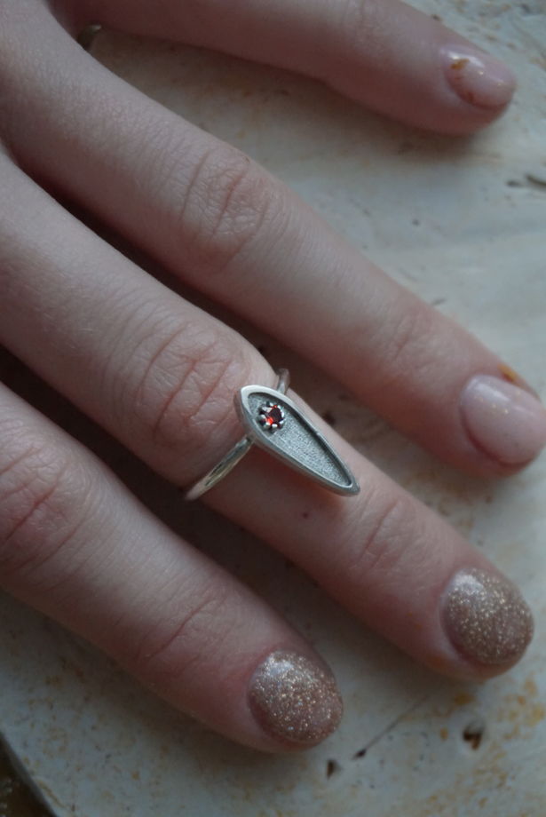 Серебряное кольцо с гранатом текстурное в форме узкой капли.