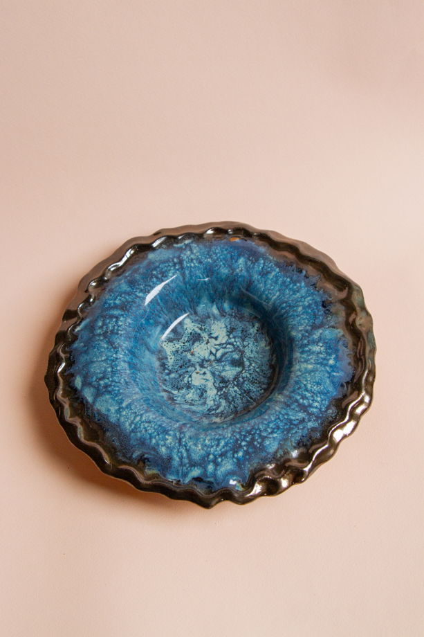 Широкополая тарелка для пасты ручной работы, выполненная из бежевой в крапинку глины, покрытая несколькими оттенками голубой и синей глазурей, а также бронзовой глазурью